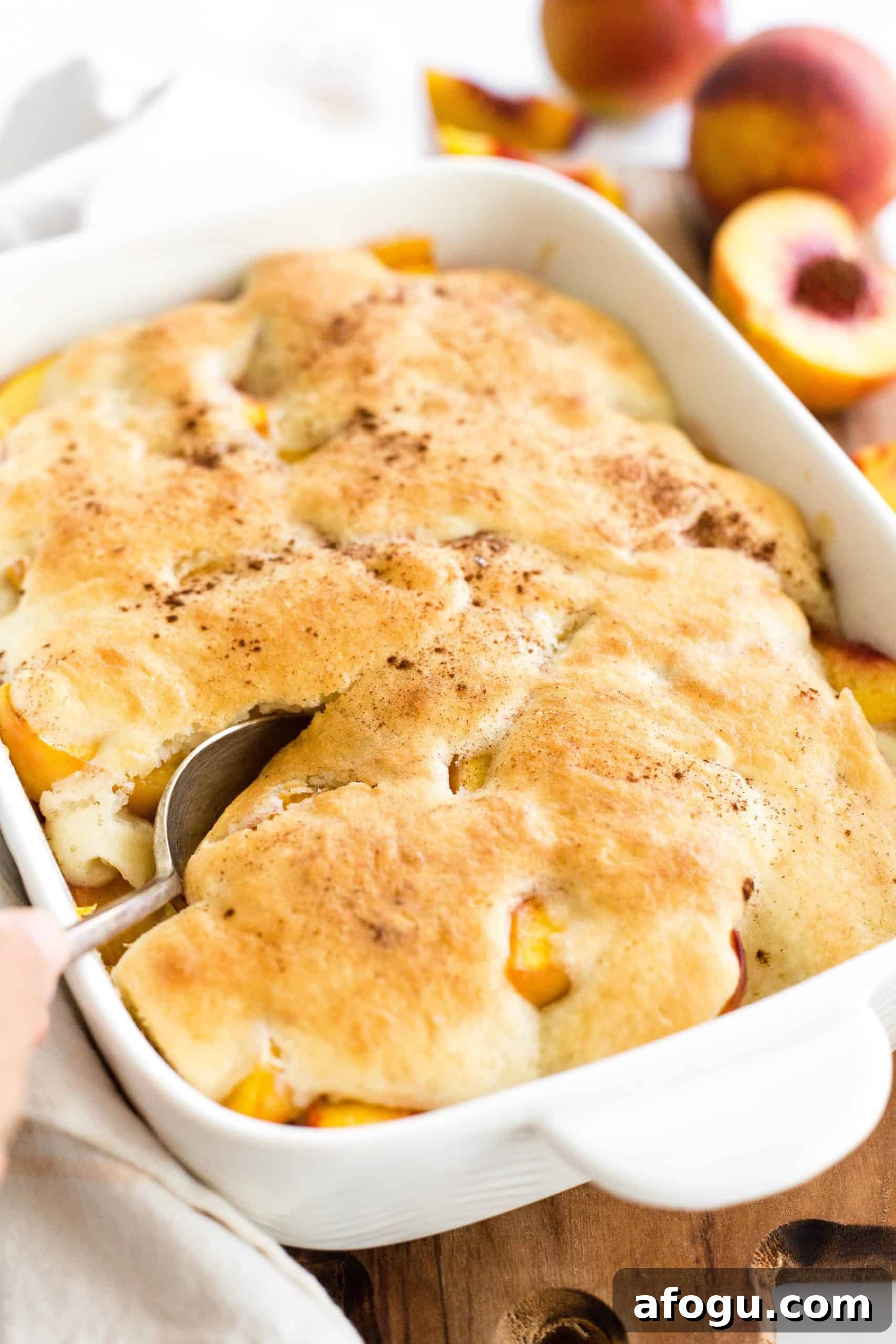 Vegan Gluten-Free Cobbler Recipe Hand holding a spoon in a gluten-free peach cobbler.