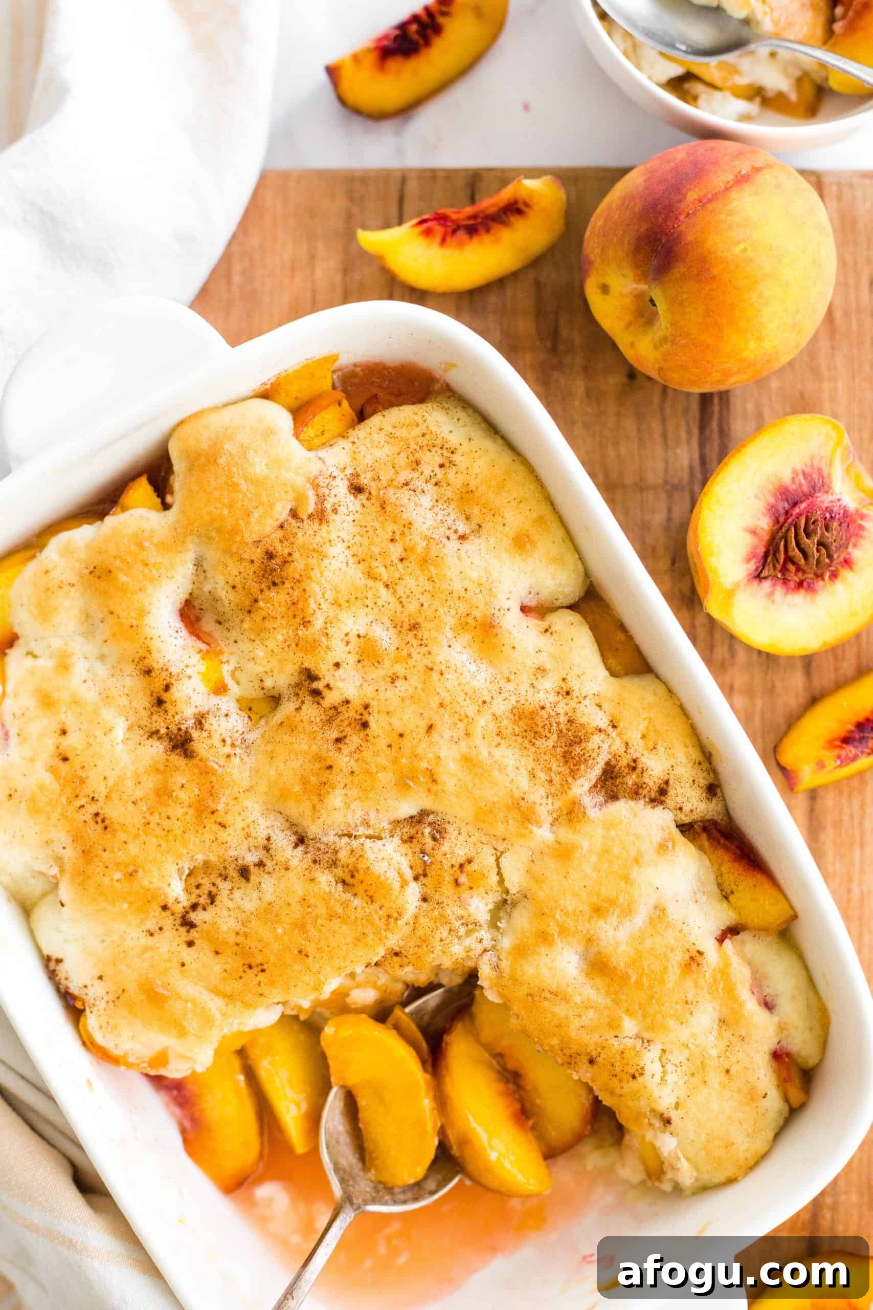 Gluten-Free Peach Cobbler with Fresh Peaches (Dairy-Free, Vegan) Baking dish with a gluten-free peach cobbler on a wooden board.