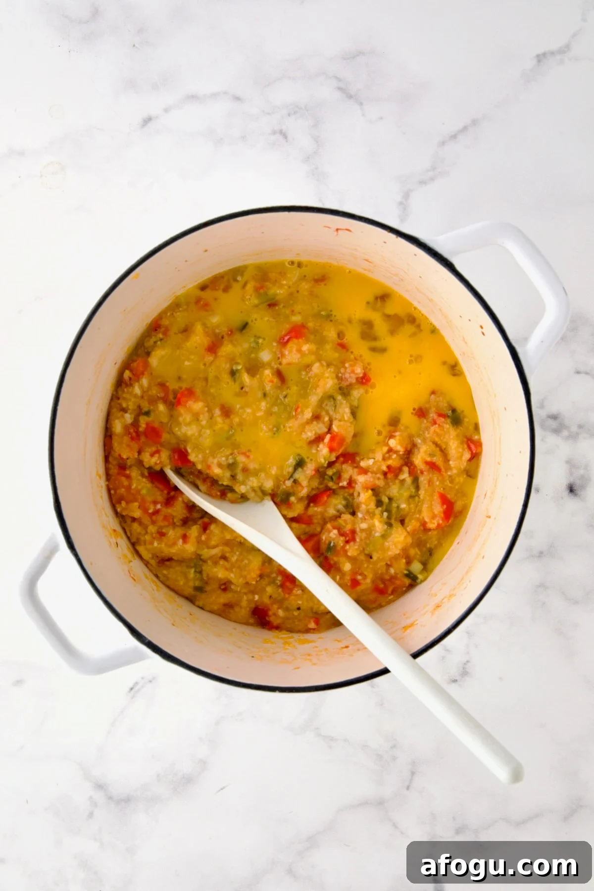 Egg added to vegetable and grits combination before being stirred in.