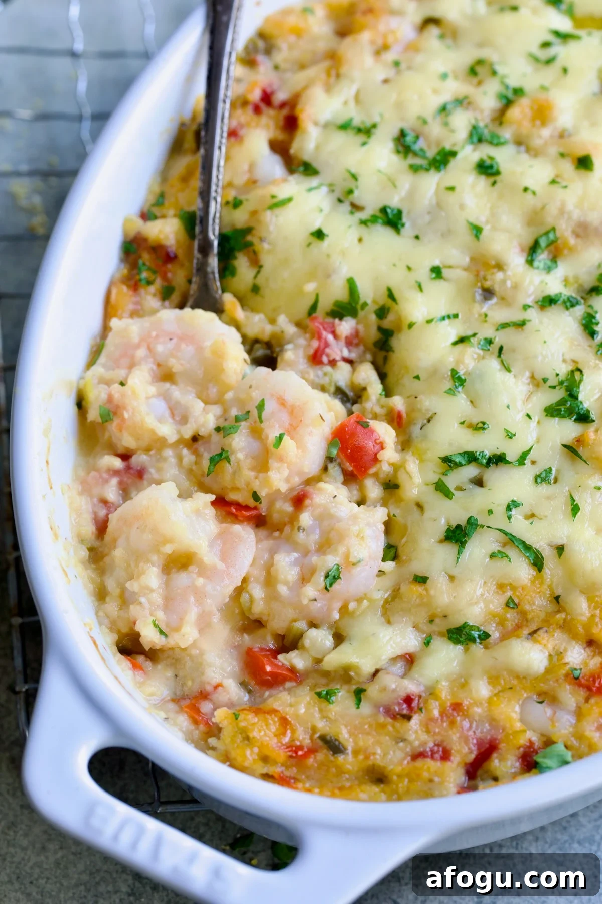 Shrimp and Grits Casserole in oval white baking dish with serving spoon.