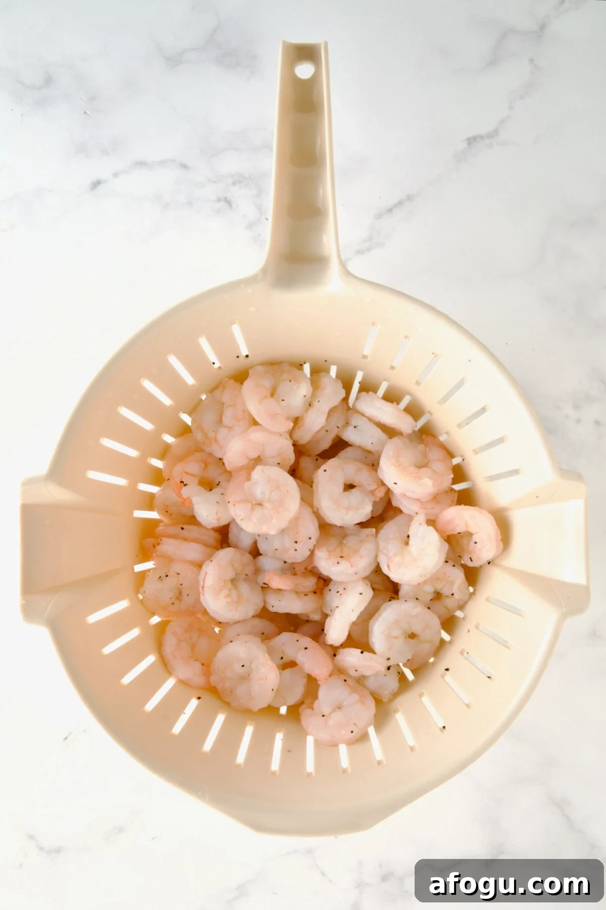 Cooked shrimp in plastic colander.