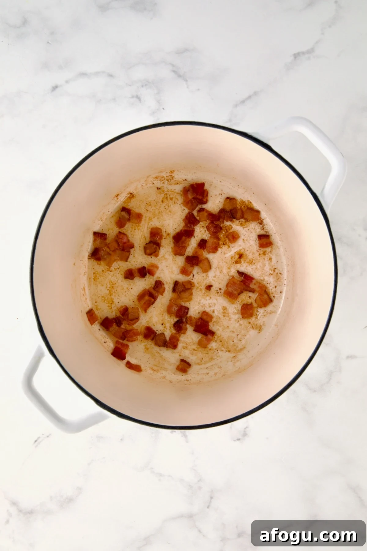 Cooked bacon in white Dutch oven.