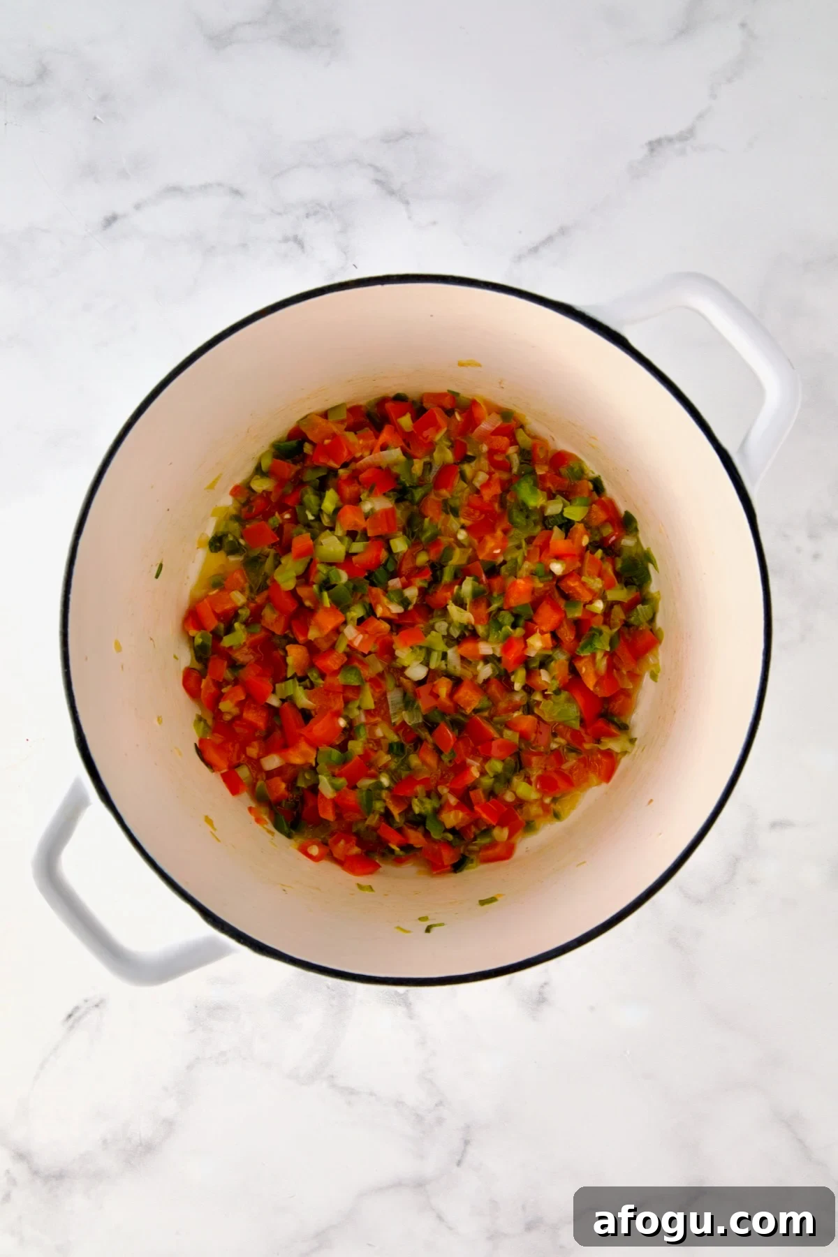 Cooked scallion, jalapeno and red bell pepper in white Dutch oven.