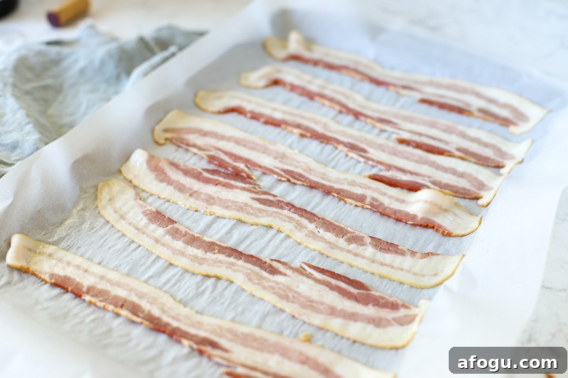 raw bacon on a baking sheet.