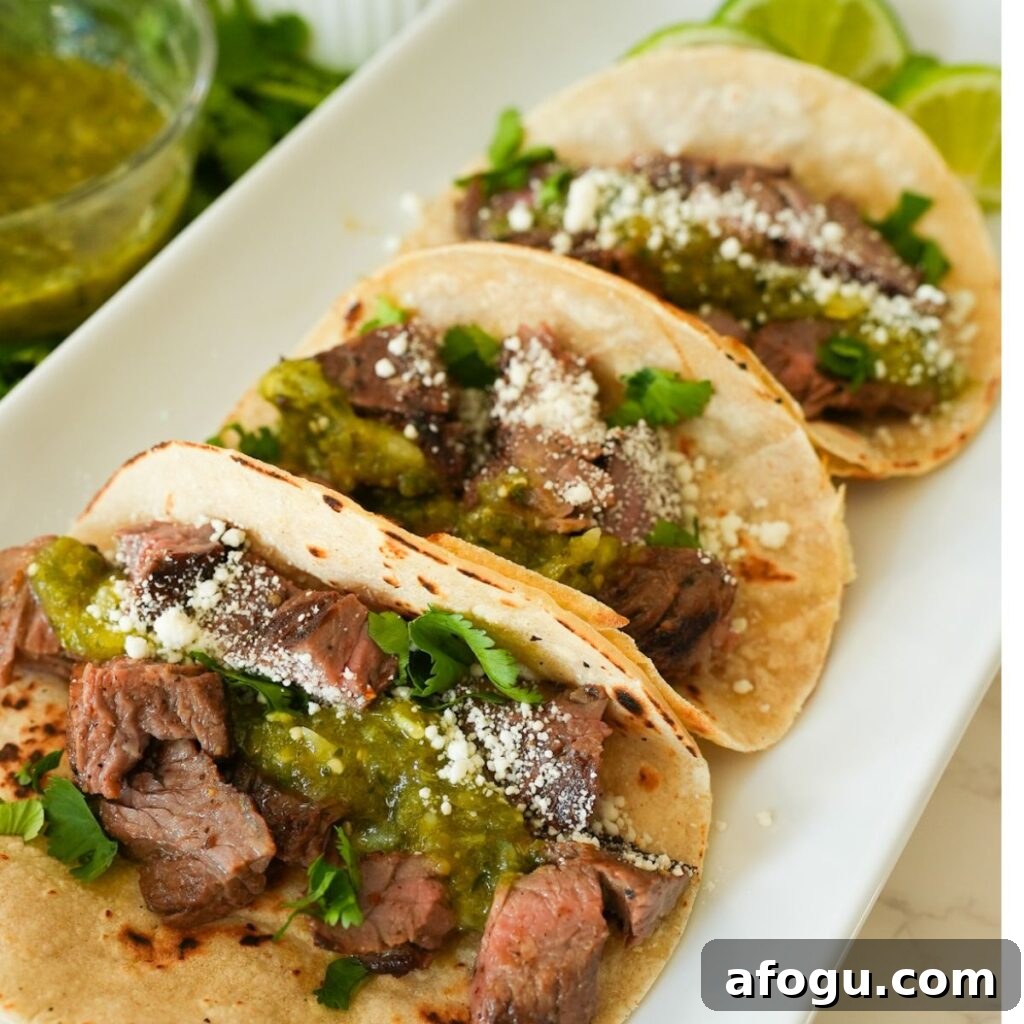 Juicy, grilled skirt steak tacos topped with cotija cheese, salsa verde, and fresh cilantro, served in warm tortillas.