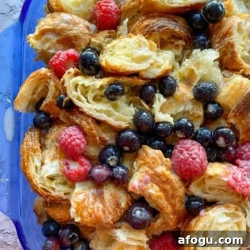 Croissant bread pudding with fruit in a baking dish, before baking.