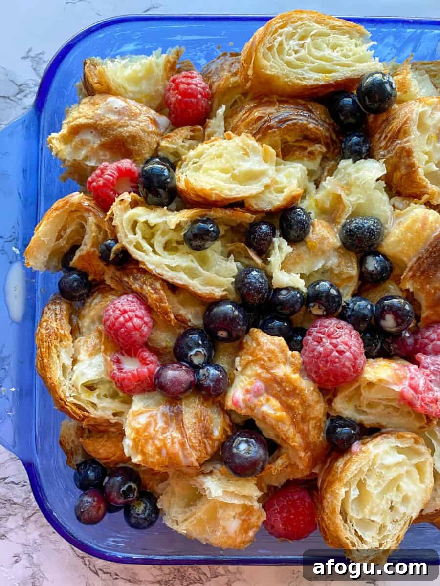 Croissants with fruit in a baking dish, before baking.