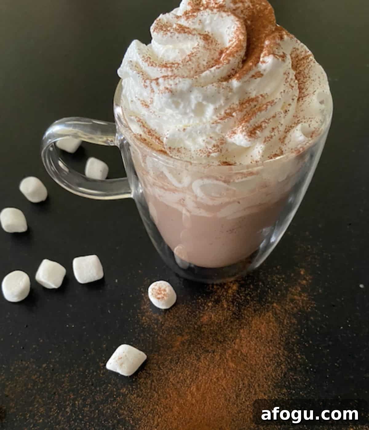 glass mug full of hot chocolate topped with marshmallows and whipped cream