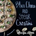Blue Cheese and Steak Crostini on wooden platter with title written on chalkboard