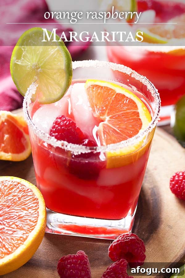 Pink cocktail in a sugar rimmed glass with text overlay - Orange Raspberry Margaritas.