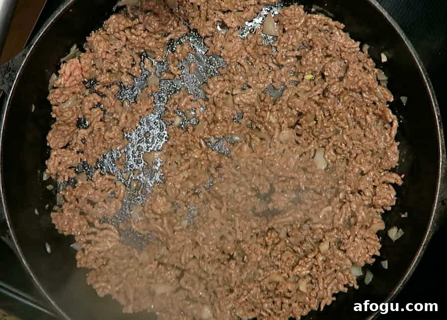 ground beef being browned in large cast iron skillet