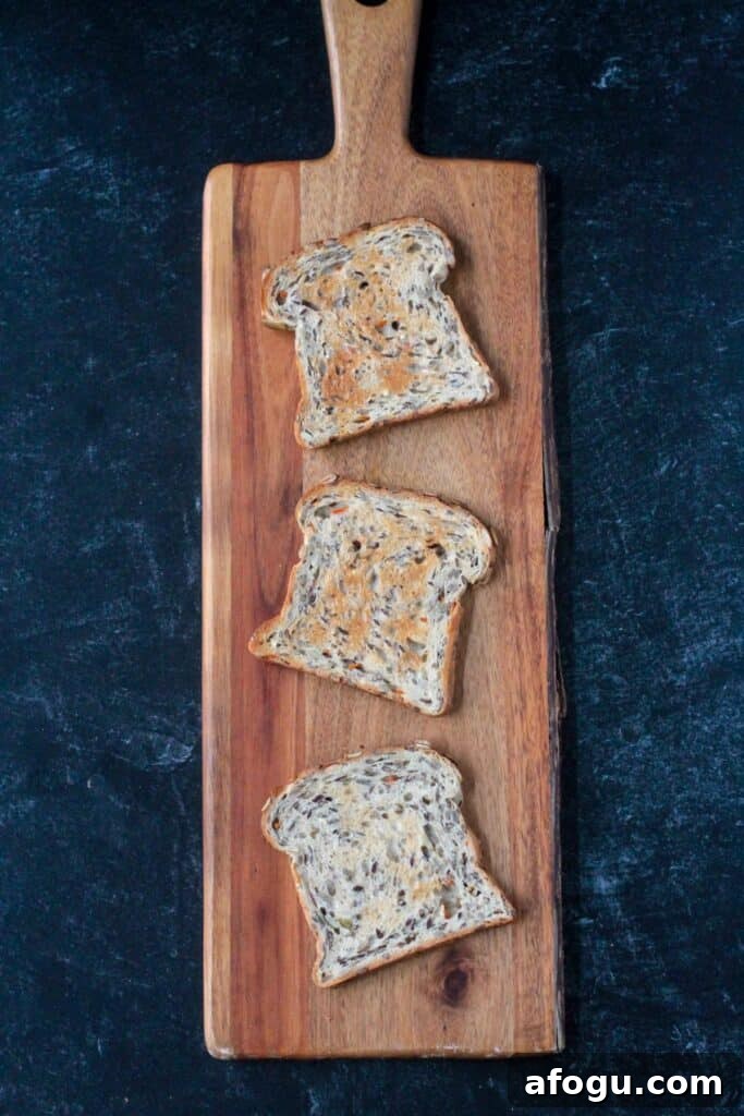 10 Creative Hummus Toast Recipes for Quick Snacks 4 Three slices of toasted breads on a wooden serving board.
