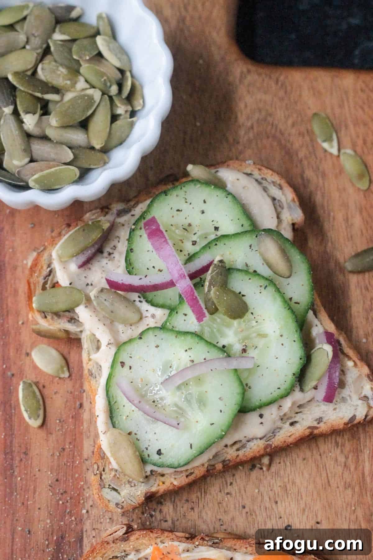 10 Creative Hummus Toast Recipes for Quick Snacks 8 Piece of toast with hummus, cucumbers, red onions, and pumpkin seeds.