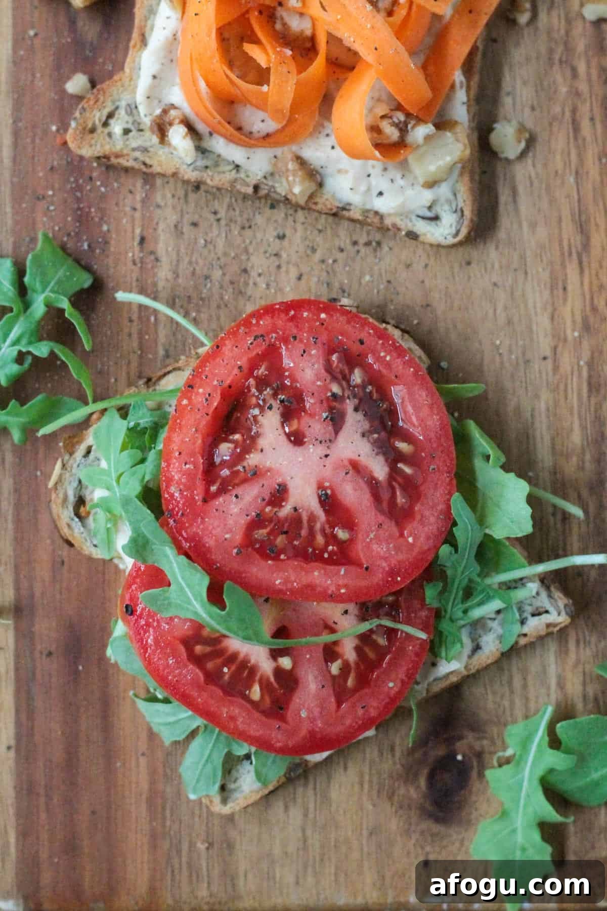 10 Creative Hummus Toast Recipes for Quick Snacks 10 Hummus toast topped with two slices of tomato and arugula.