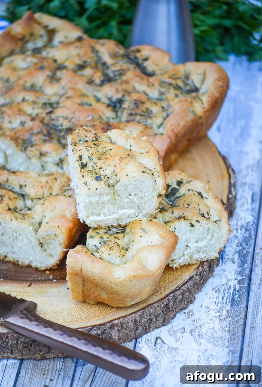 pieces of quick easy focaccia bread stacked on a wooden cutting board