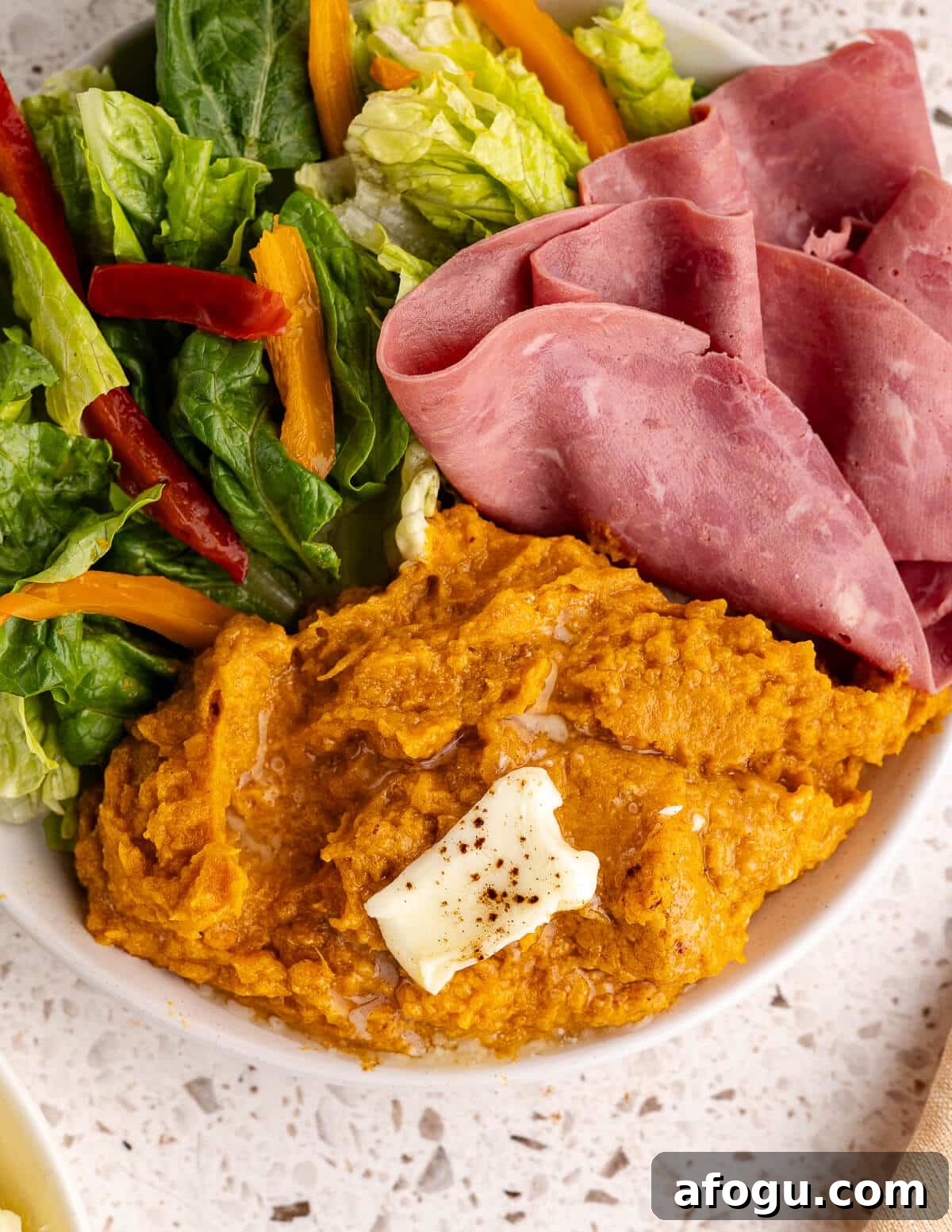 mashed sweet potatoes with sliced ham and salad. 