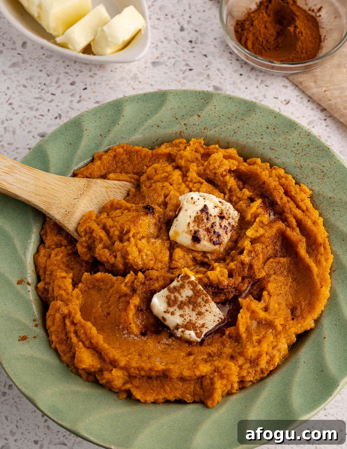 a bowl full of mashed sweet potatoes with maple syrup, butter, and cinnamon on top. 
