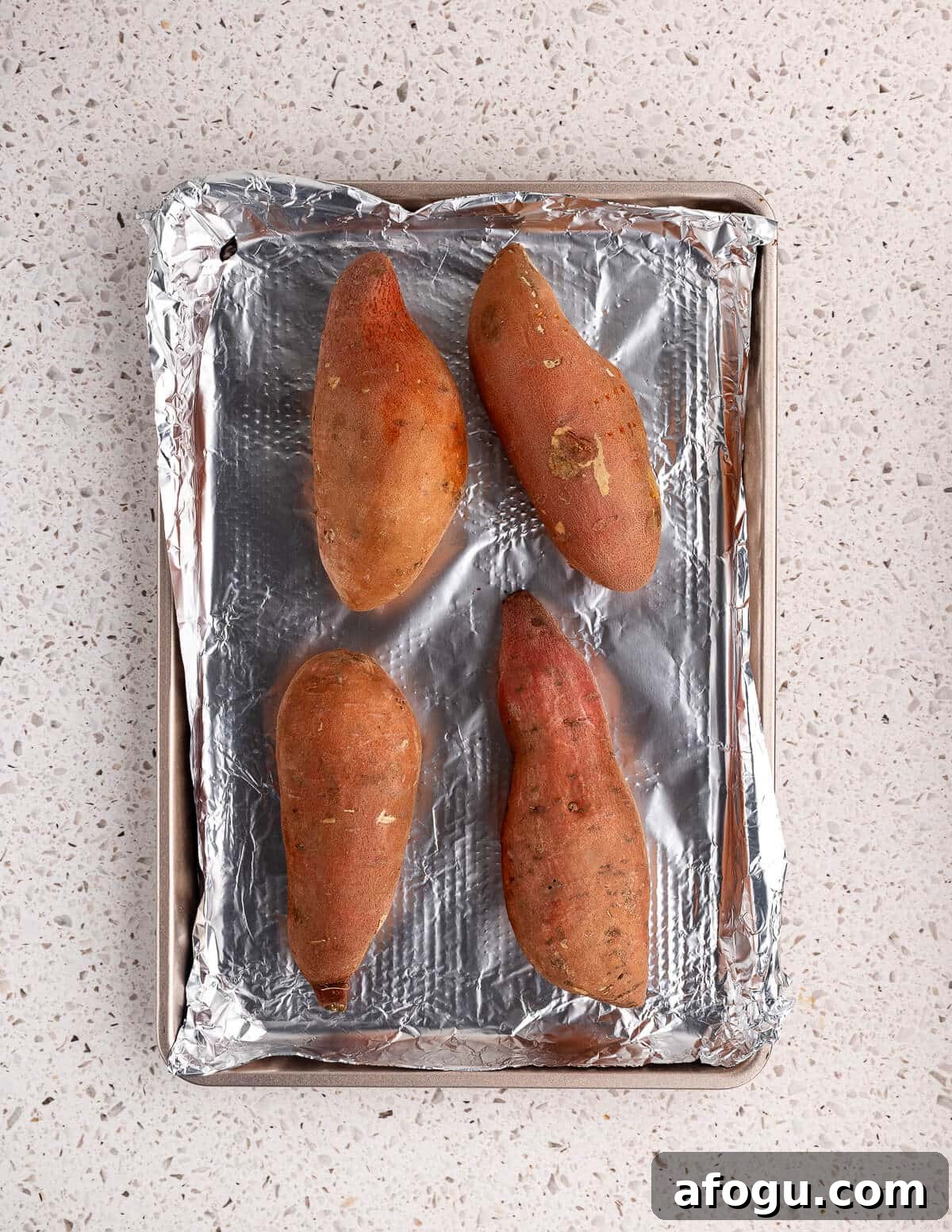 sweet potatoes on an aluminum foil lined sheet pan.