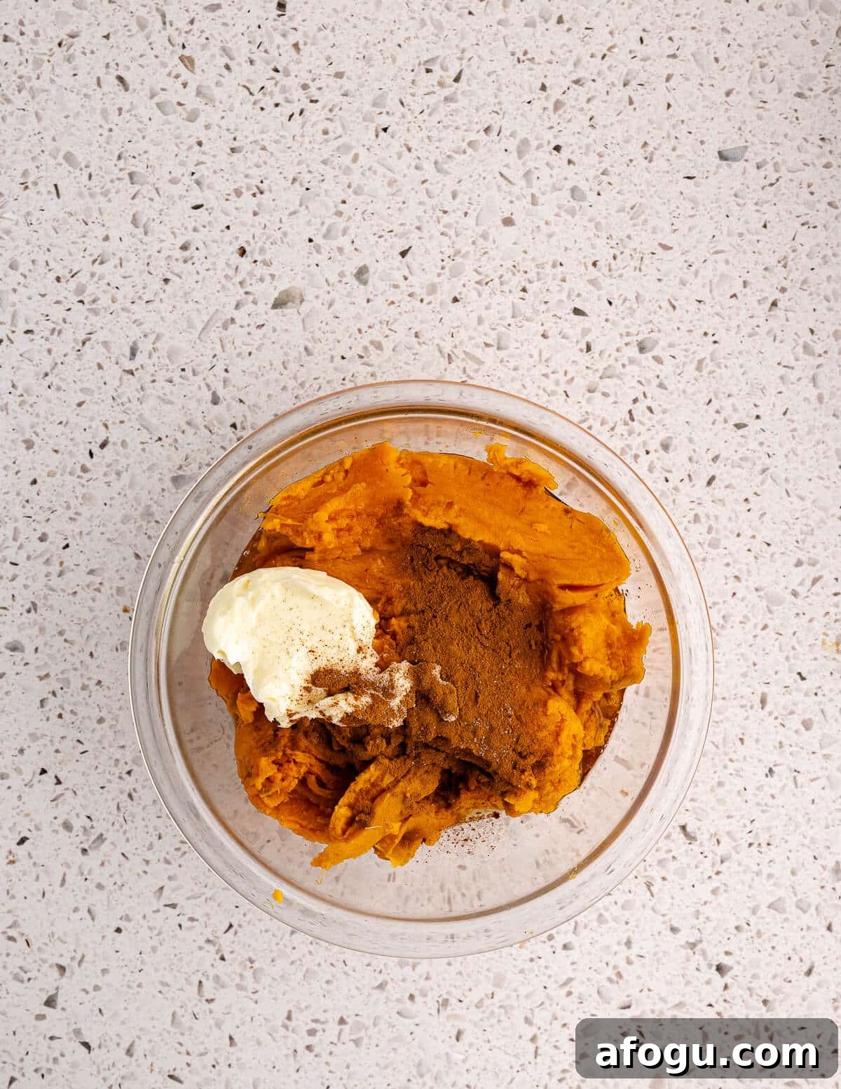 cooked sweet potatoes in a bowl with butter and cinnamon on top. 