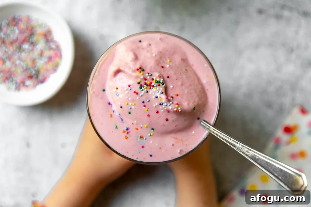 Overhead shot of strawberry frozen yogurt in a glass with sprinkles on top.