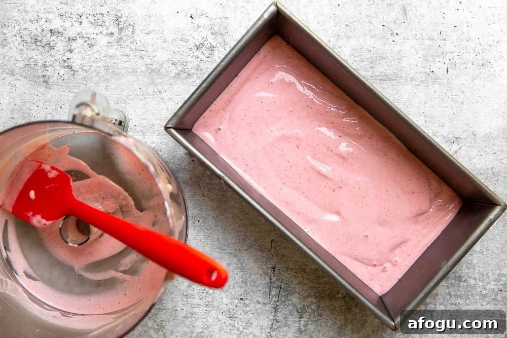 Process shot showing strawberry frozen yogurt being scraped into a loaf pan to chill.