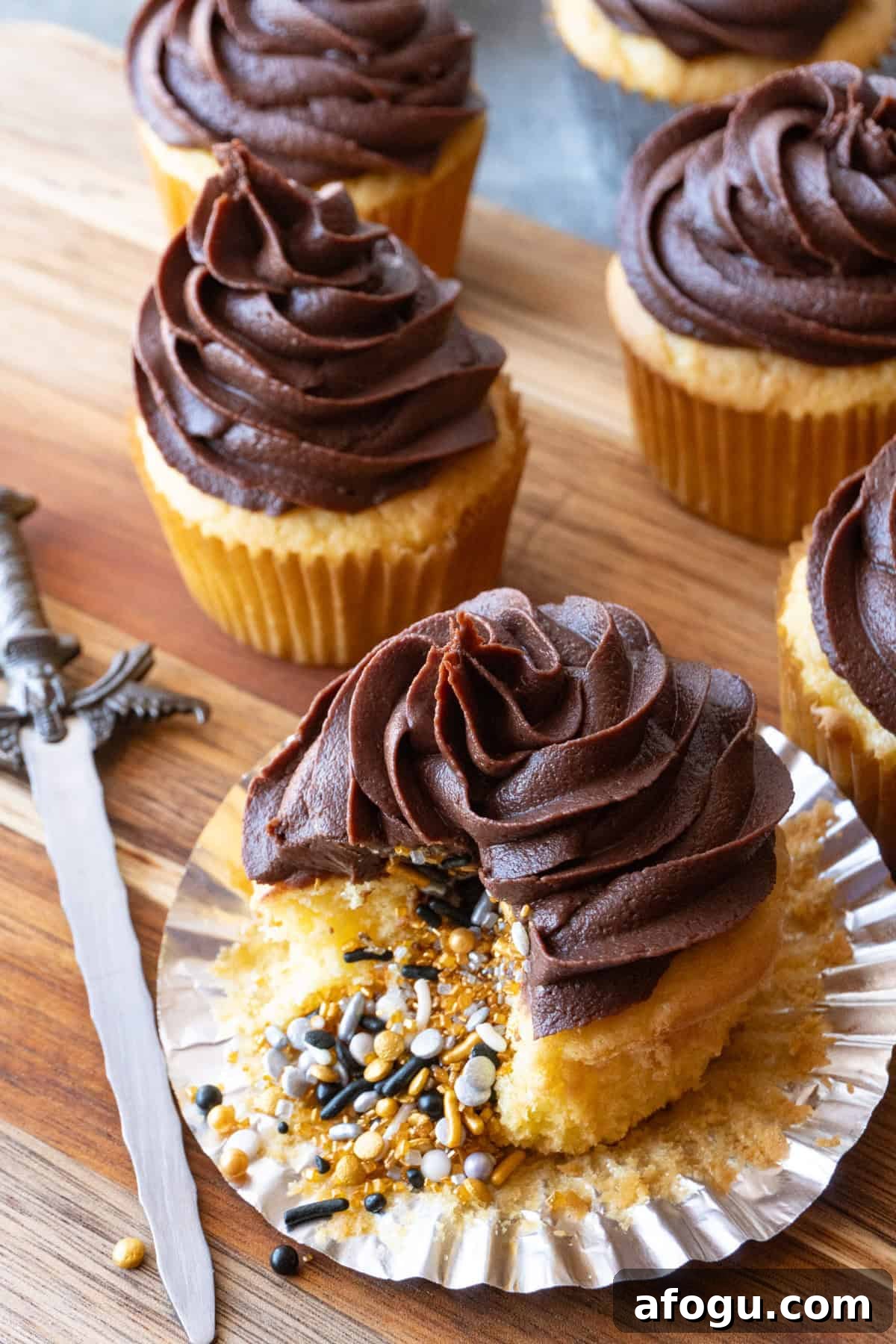 yellow cupcake with gold, silver, and black sprinkles