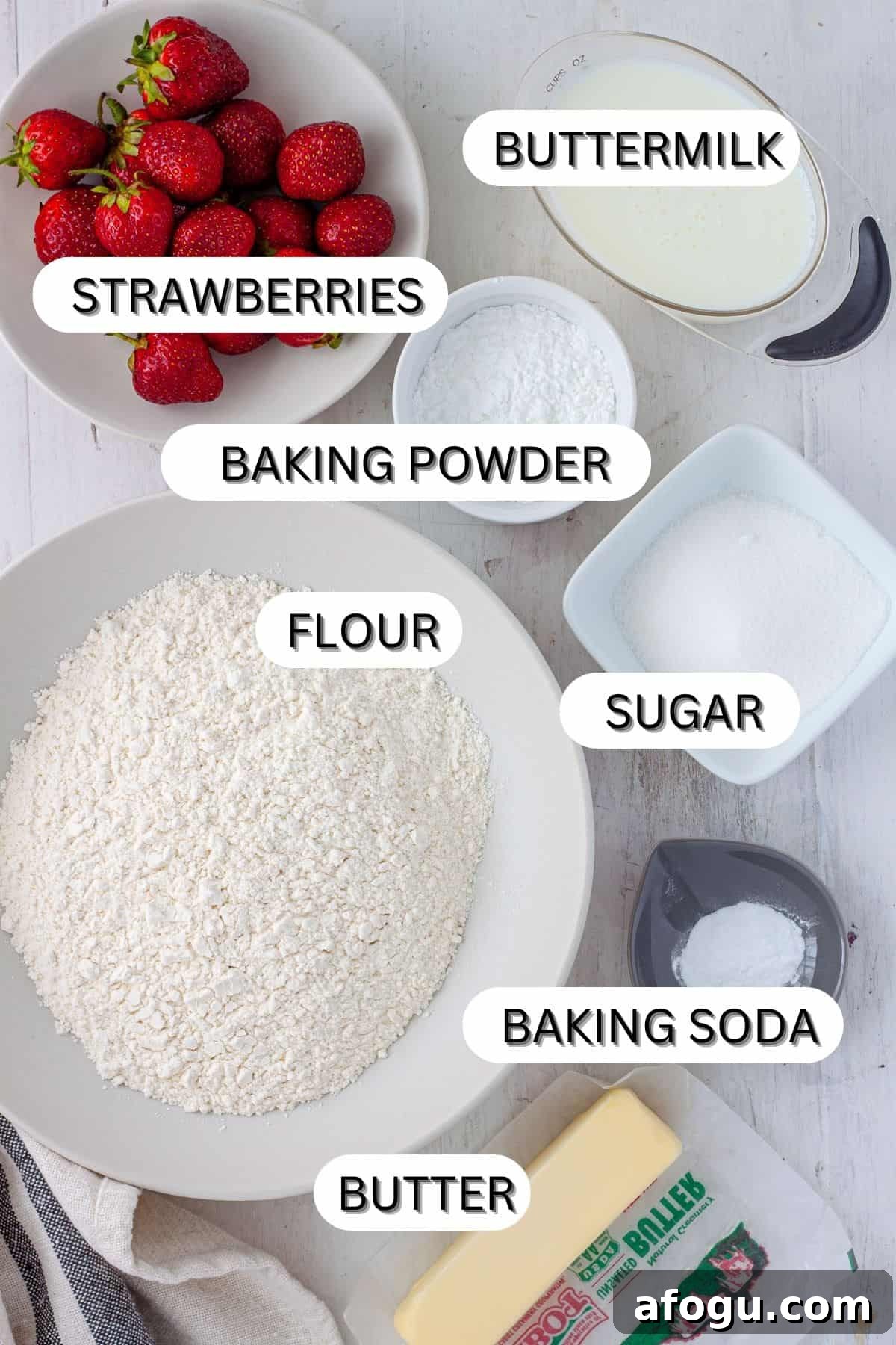 Ingredients for strawberry biscuits on a white table.