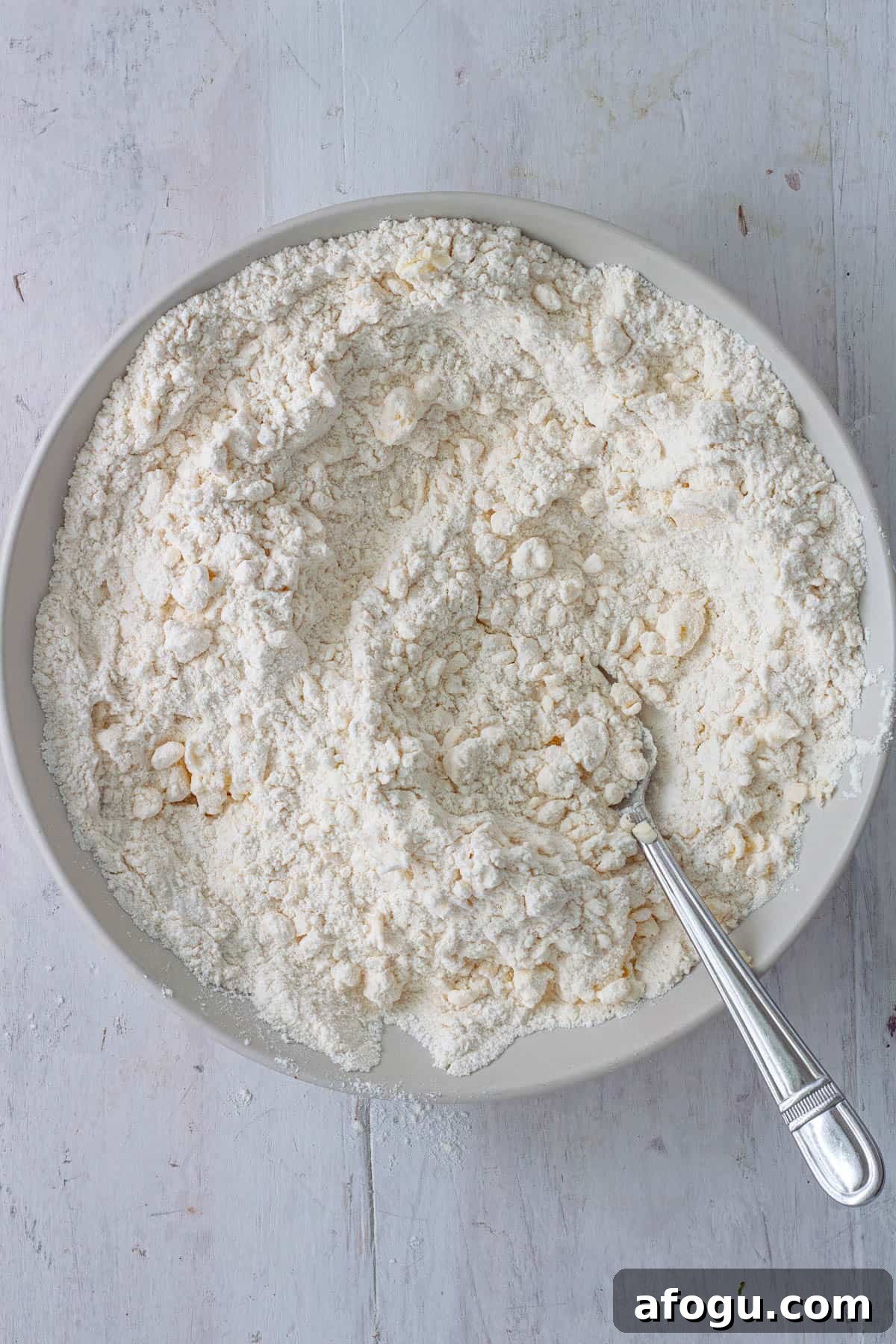 Butter getting cut into flour for biscuits.