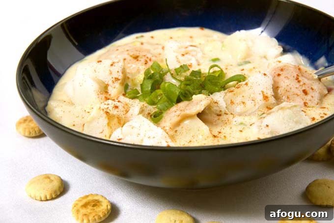 Spanish Nochebuena Christmas Dinner Menu and Traditions 3 Spanish Fish Chowder garnished with green onions, in a black bowl, on a white surface with scattered oyster crackers.