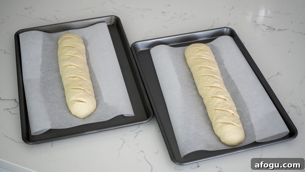 Two unbaked loaves of garlic bread, slit across the top diagonally.