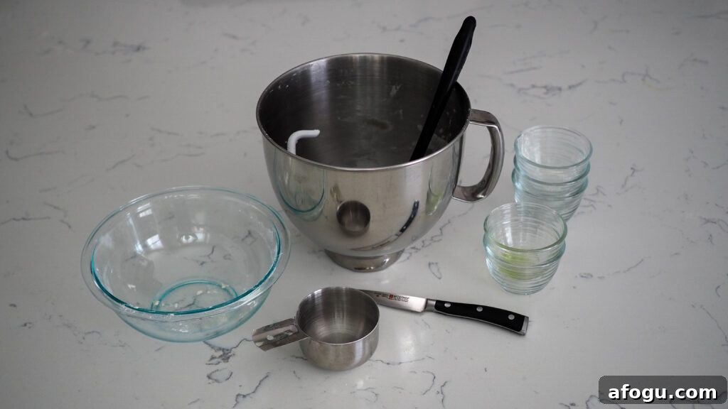 A mixer bowl, dough hook, knife, and assortment of bowls on a counter.