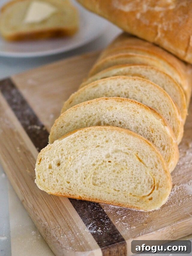 A sliced loaf of garlic French bread with another loaf resting on top of it.
