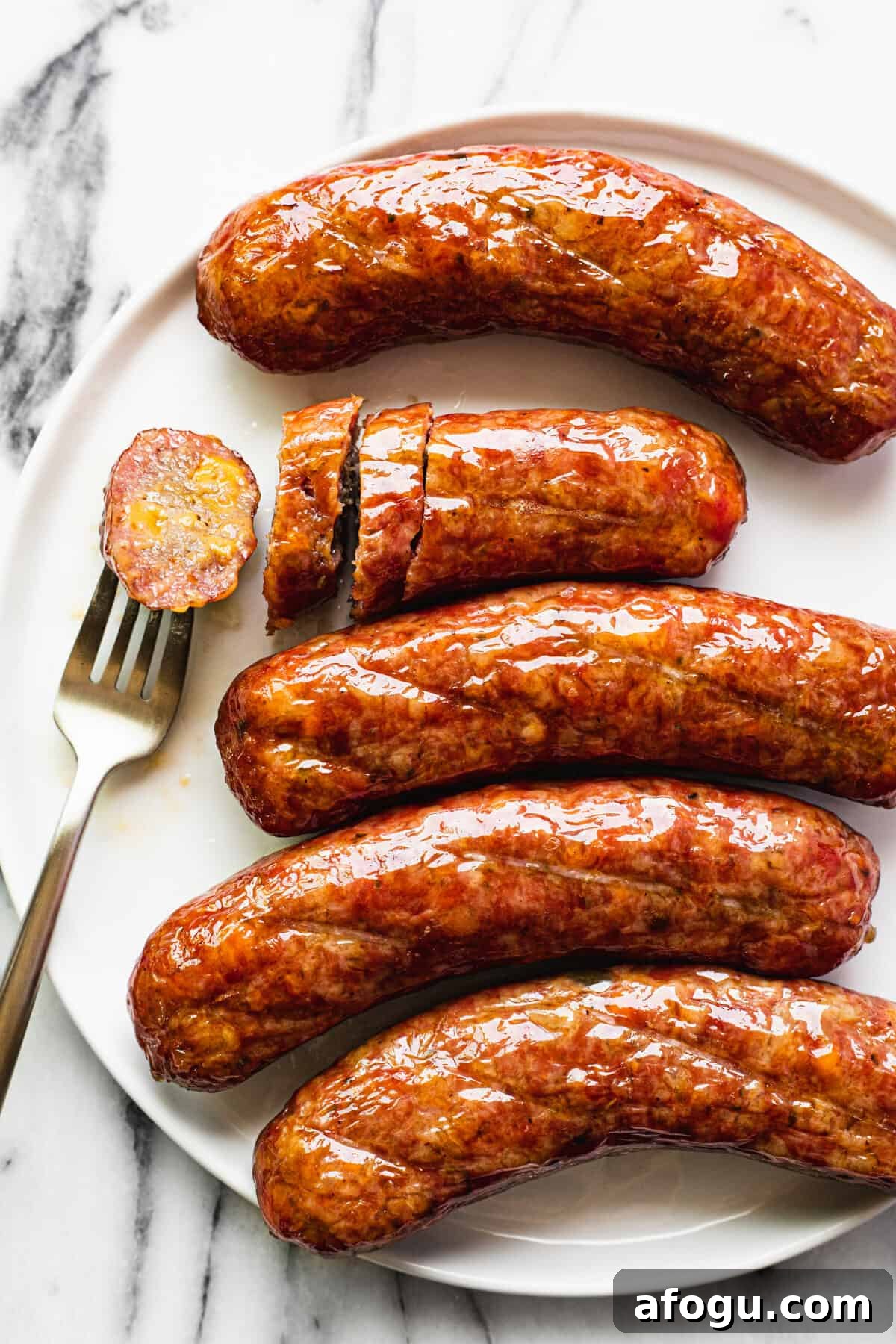 White plate with smoked cheddar jalapeno brats that are sliced.
