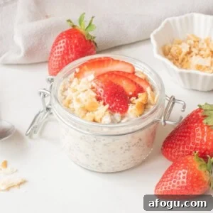 Strawberry Cheesecake Overnight Oats Recipe for Creamy Make-Ahead Breakfast 9 Strawberry cheesecake overnight oats in a glass jar topped with sliced strawberries and graham cracker crumbs.
