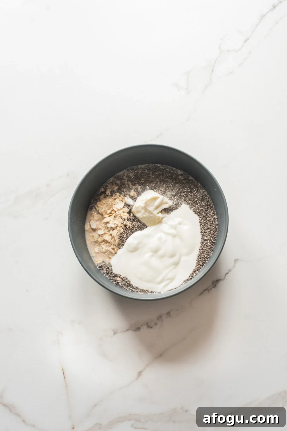 Strawberry Cheesecake Overnight Oats Recipe for Creamy Make-Ahead Breakfast 5 Overnight oats ingredients including oats, chia seeds, cottage cheese, and cream cheese in a bowl before mixing.