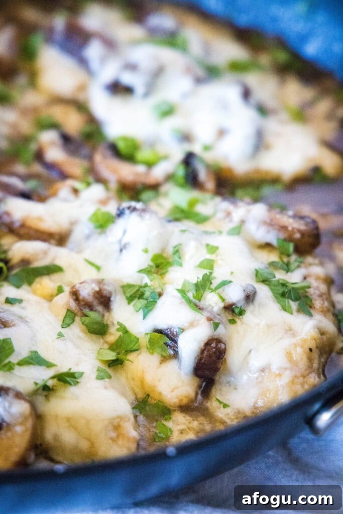 chicken with melted cheese and parsley in a skillet
