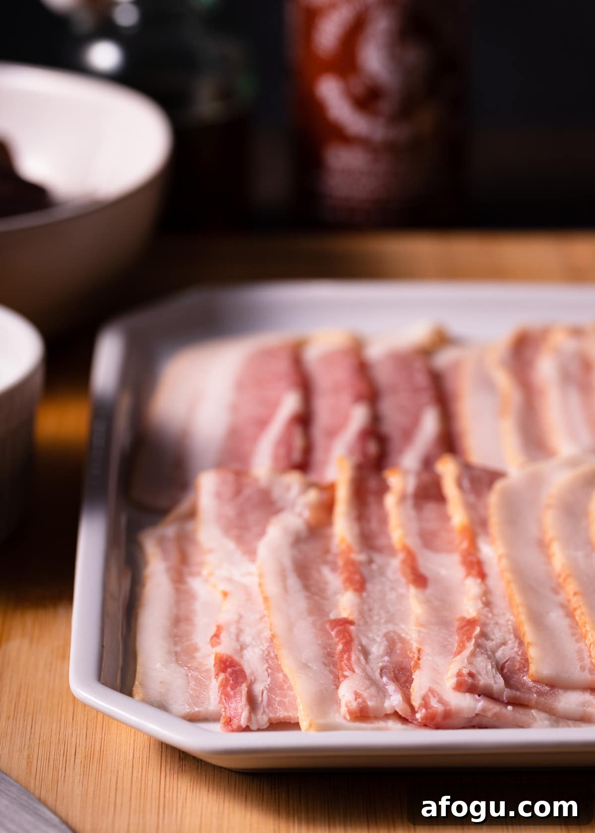 raw bacon strips on a white platter