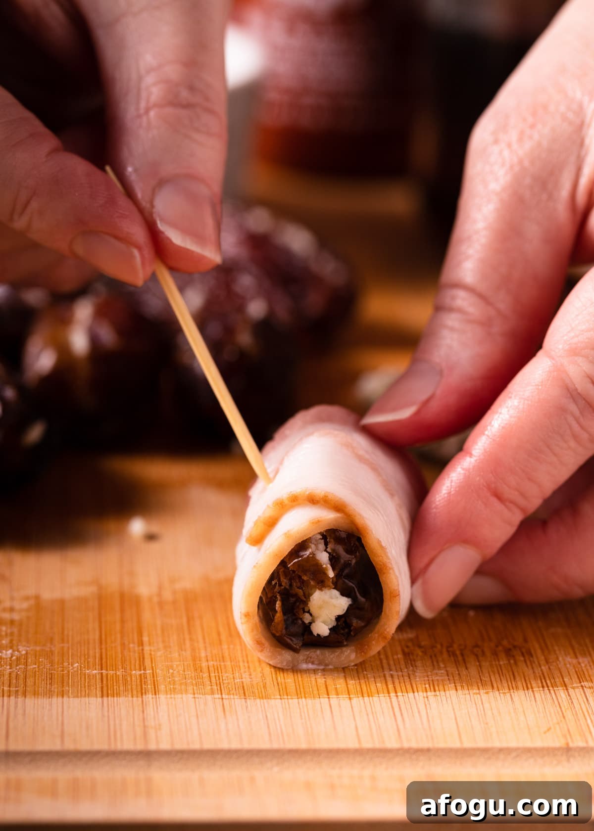 bacon wrapped date being skewered closed with a soaked toothpick