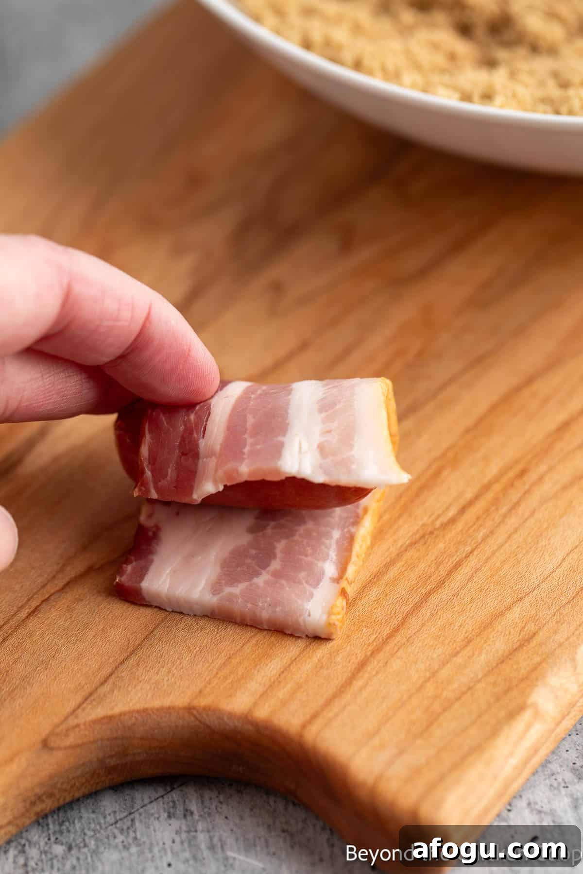 Wrapping a little smokie with a piece of bacon.