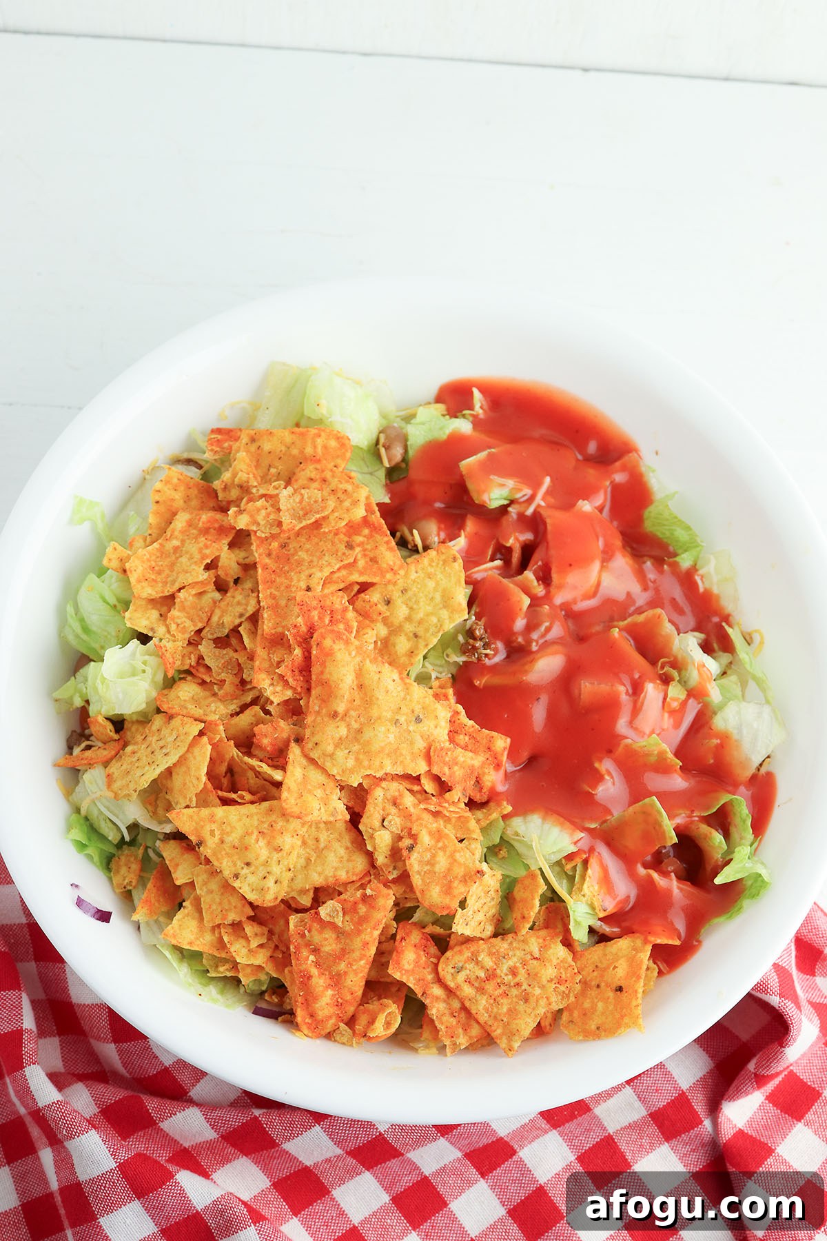 Crushed Doritos and Catalina dressing are added to the taco meat mixture in a bowl.