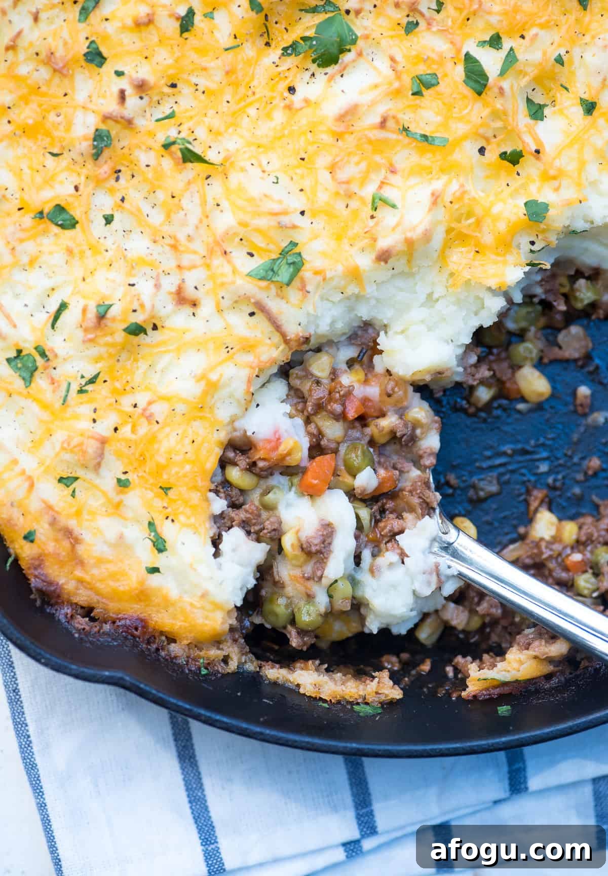 A spoon scoops up Shepherd's Pie from a skillet.