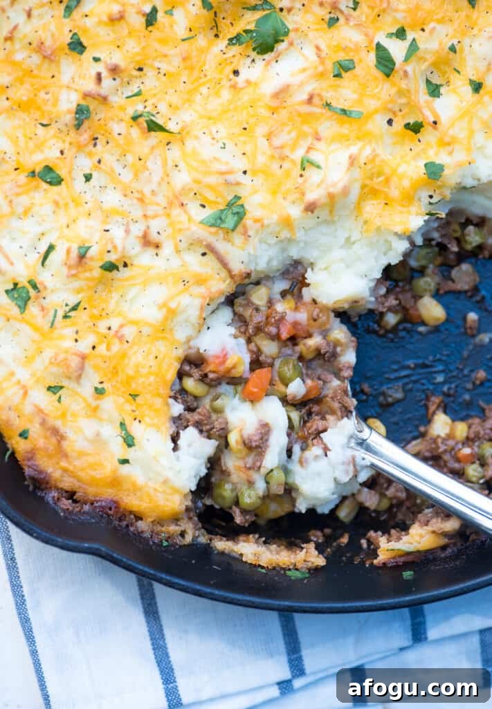 A spoon scoops up Shepherd's Pie from a skillet.