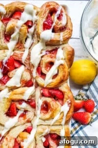 Overhead shot of strawberry cinnamon rolls in a large baking dish on a white counter.