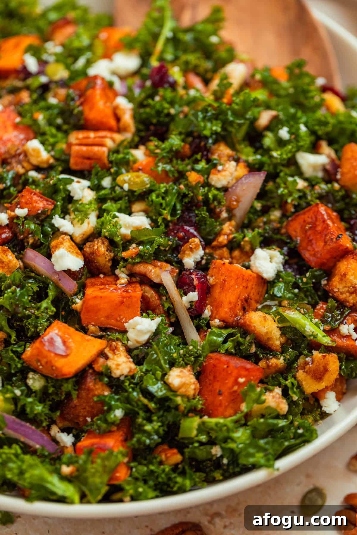Sweet potato kale salad in serving platter topped with feta, cornbread croutons and more.