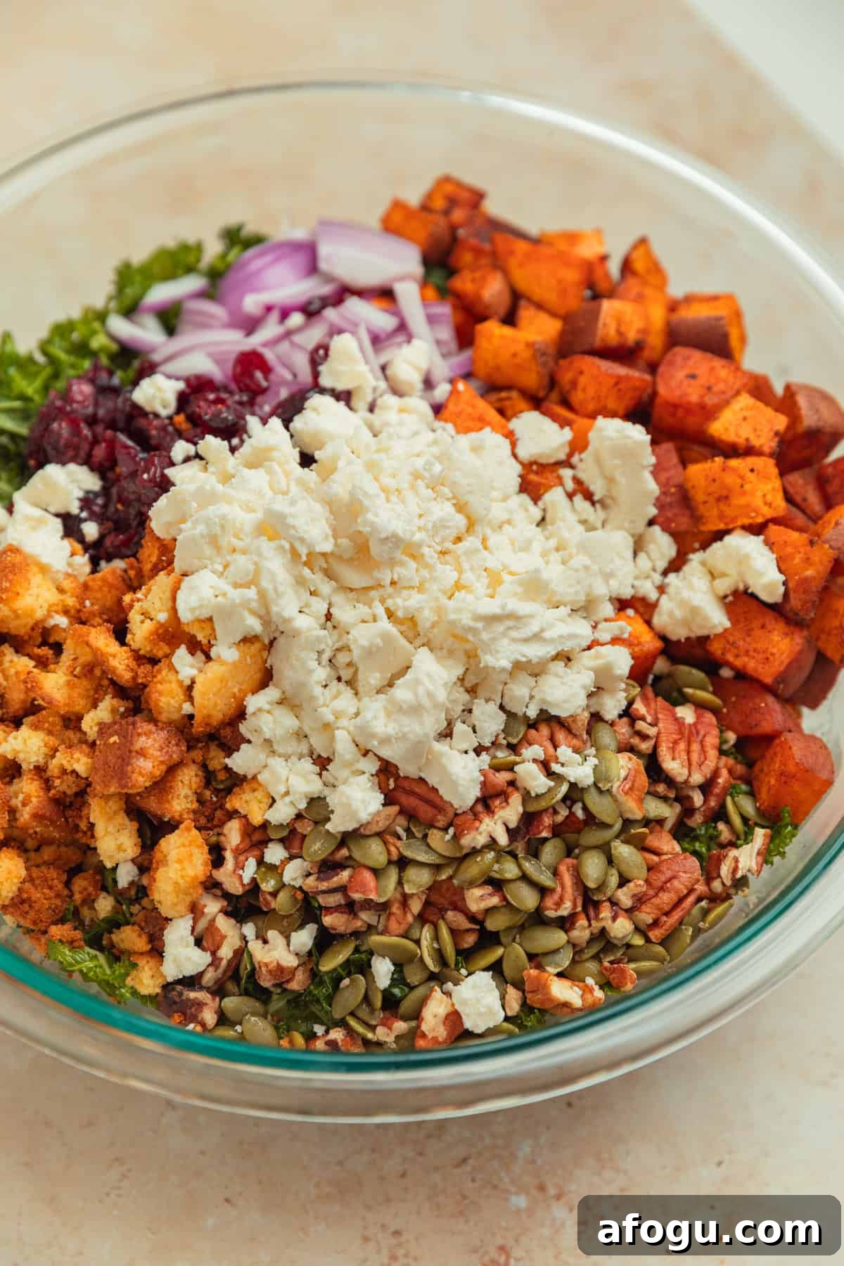 Kale salad in bowl with cornbread croutons, cranberries, sweet potatoes and feta. 