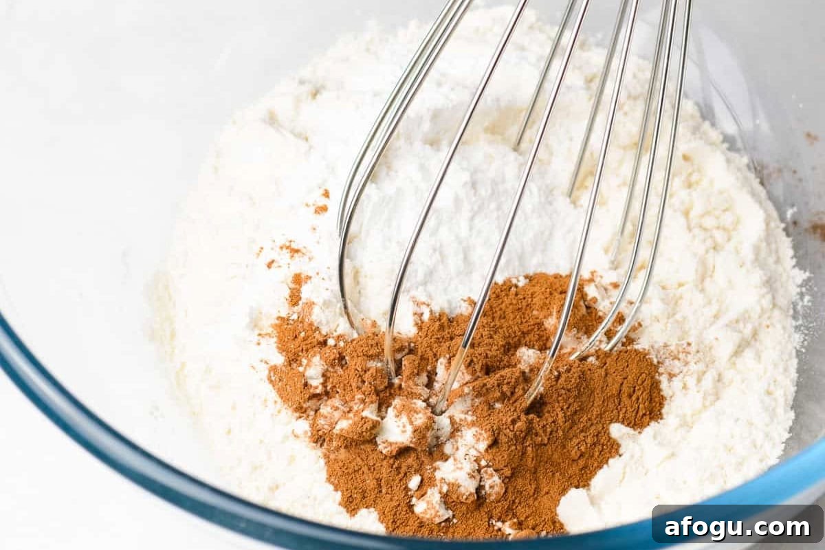 flour and cinnamon in a glass bowl with a whisk.