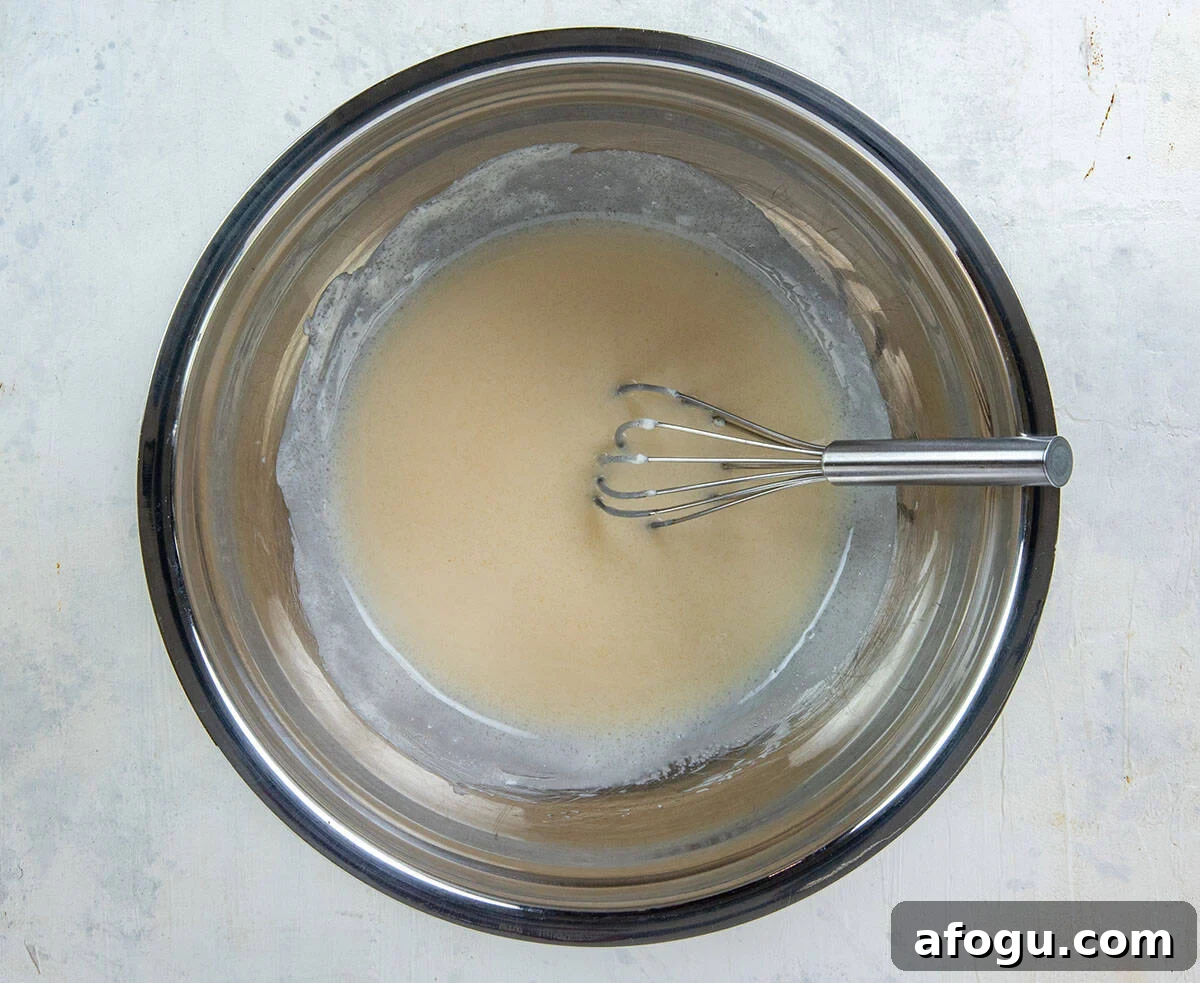 Mayonnaise, sugar, and vinegar stirred together in a bowl with a whisk.