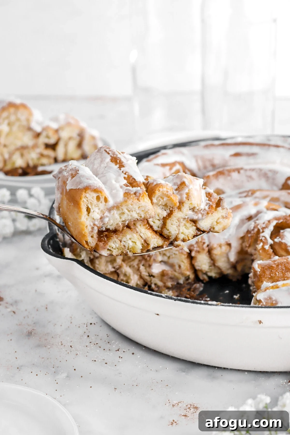 slice of cinnamon roll being held above skillet.