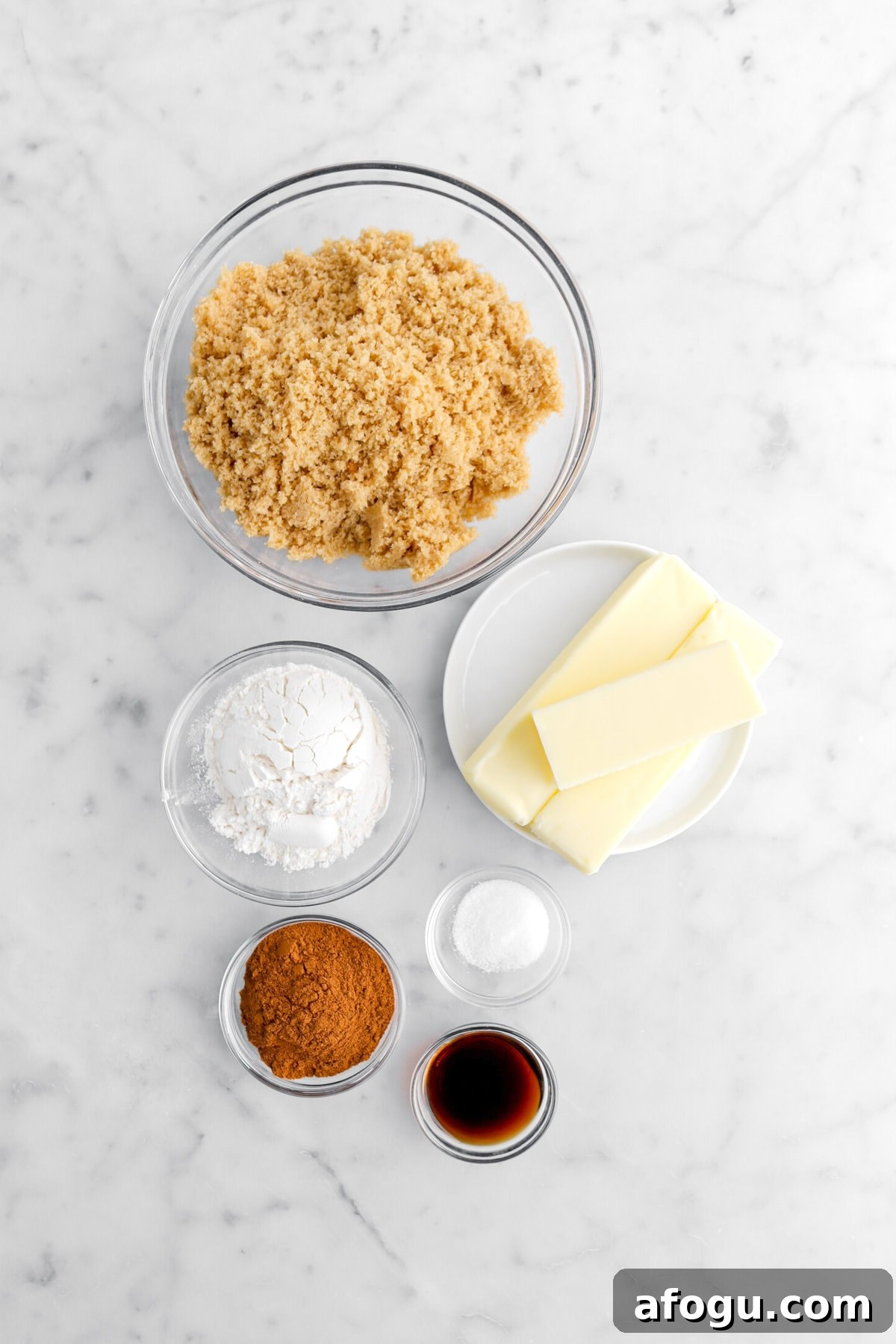 brown sugar, butter, flour, salt, cinnamon, and vanilla on marble surface.