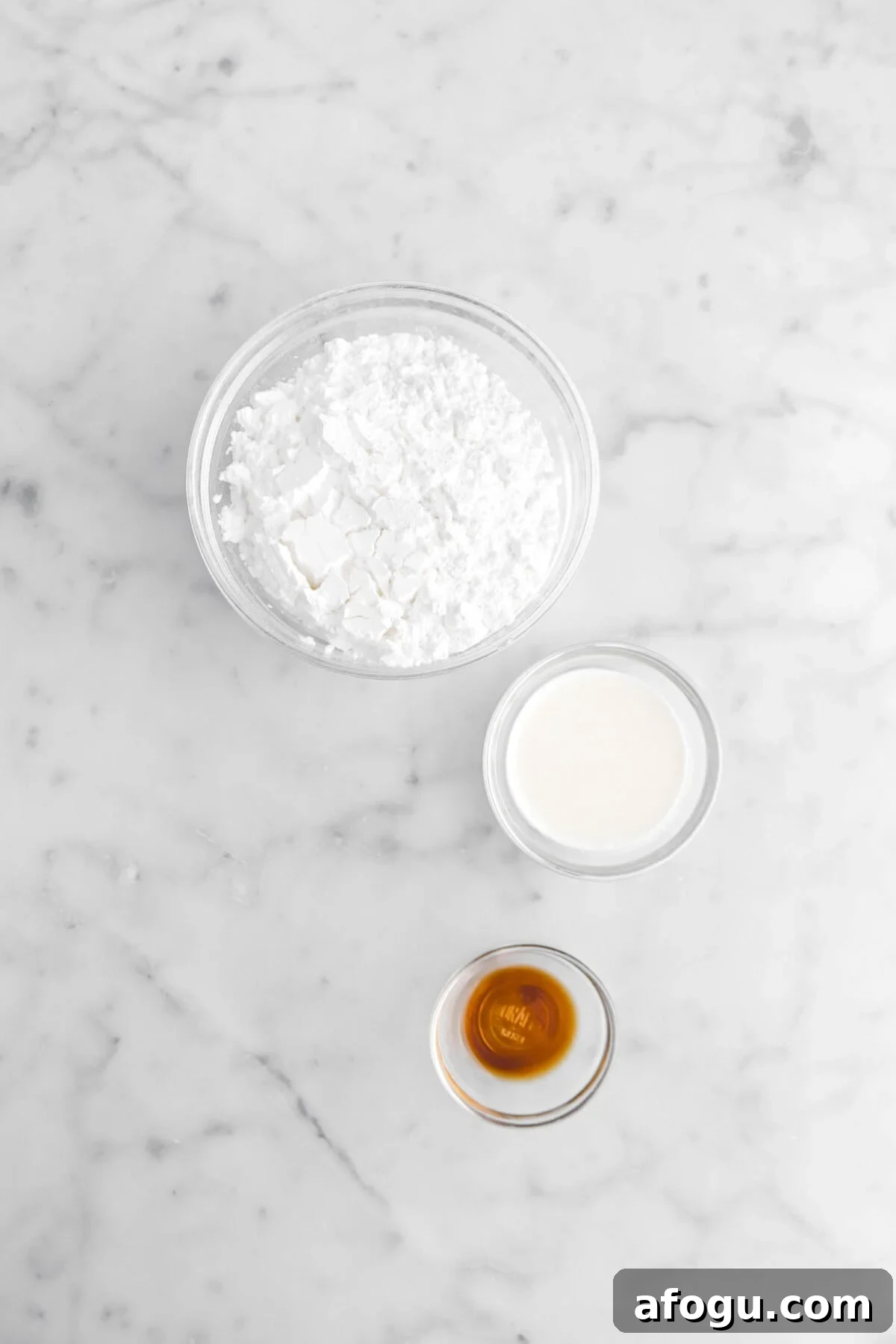 powdered sugar, milk, and vanilla on marble surface.